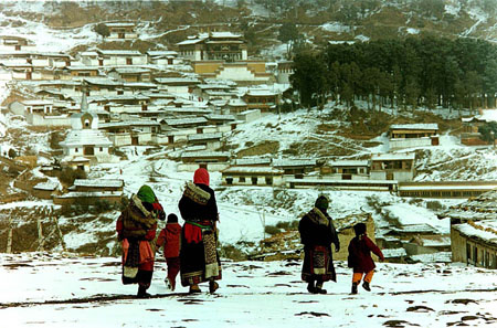 身穿鲜艳藏服的妇女儿童踏雪转寺庙